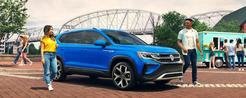 a couple walking out of their blue Volkswagen Taos