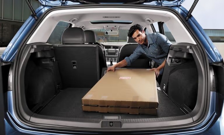 a man loading a large box into his Volkswagen