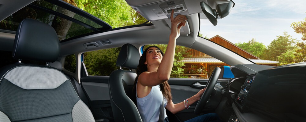 woman inside her Volkswagen opening the sunroof