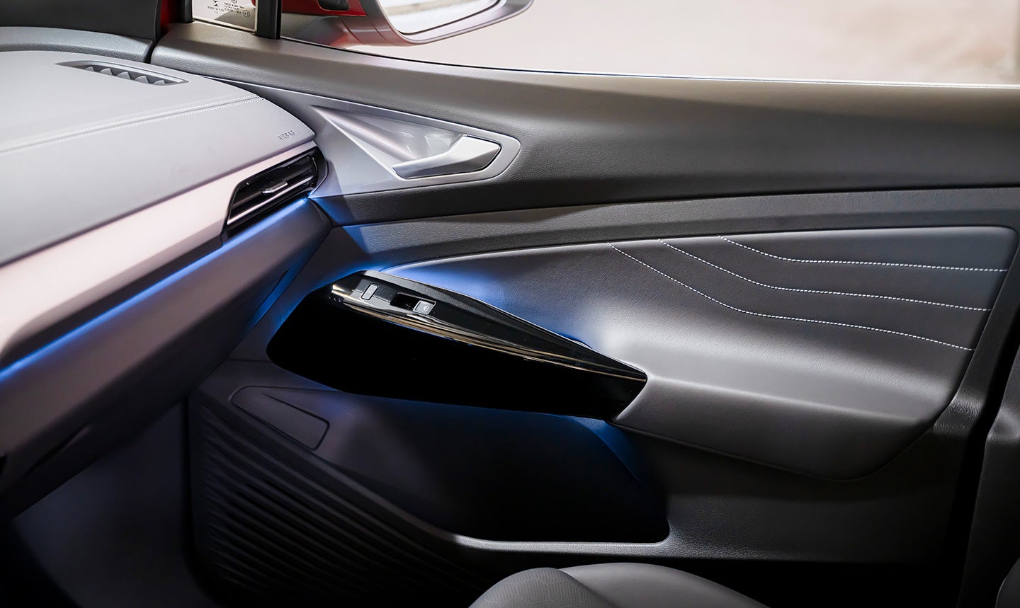 An interior shot of an ID.4 showing blue glow of ambient lighting along dash and door, with focus on the passenger-side door.